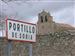 en esta foto se ve la iglesia romanica con el cartel de portillo a la entrada por el camino de torru